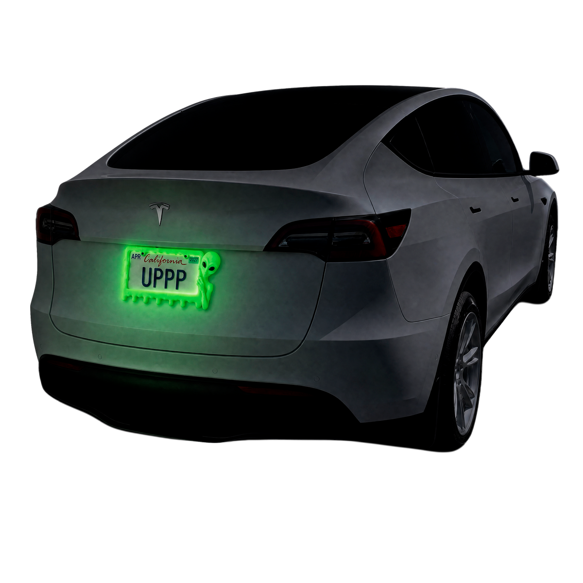 White Tesla with a UPPP alien license plate frame glowing green in the dark at night