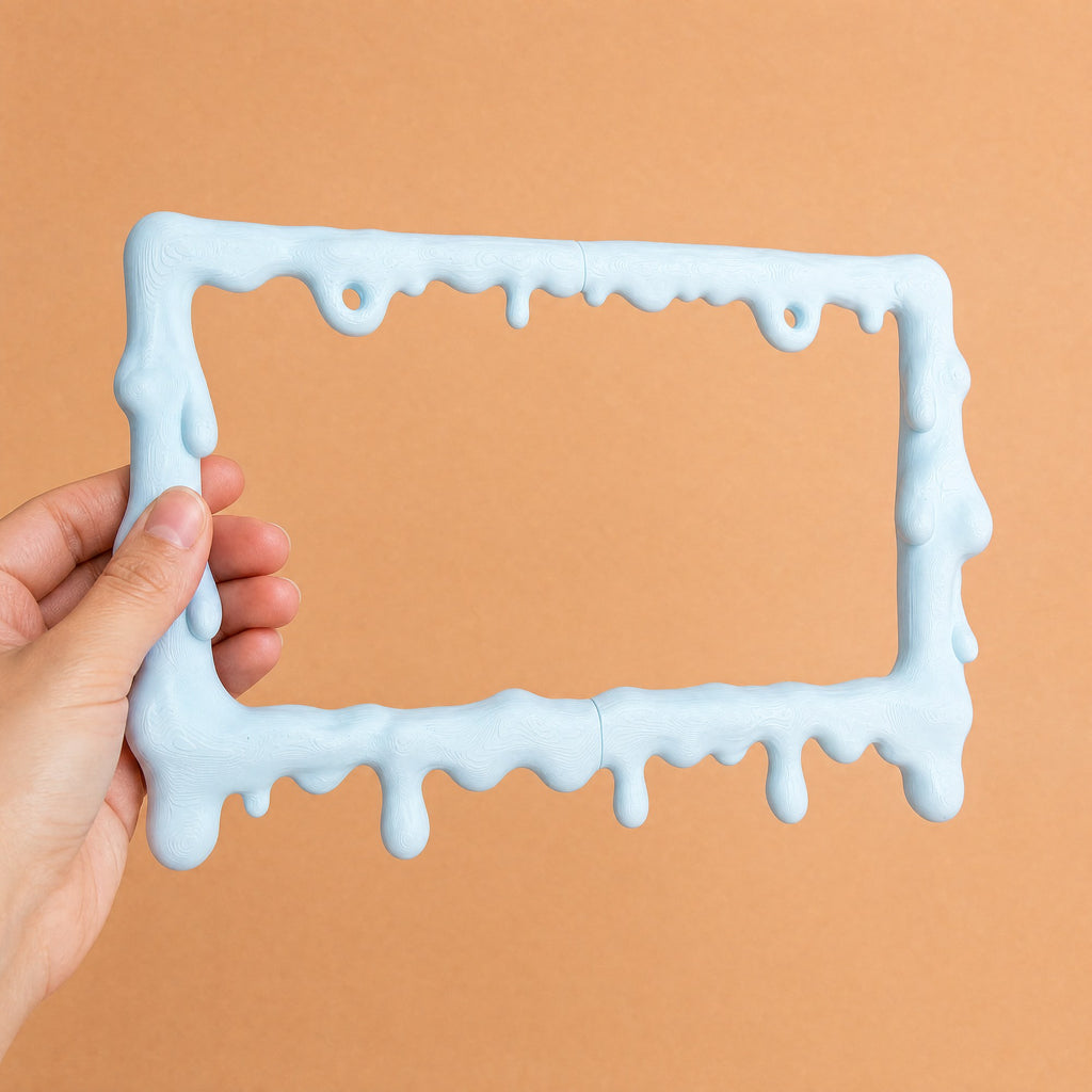 Baby blue drip license plate frame held in a hand to show its size