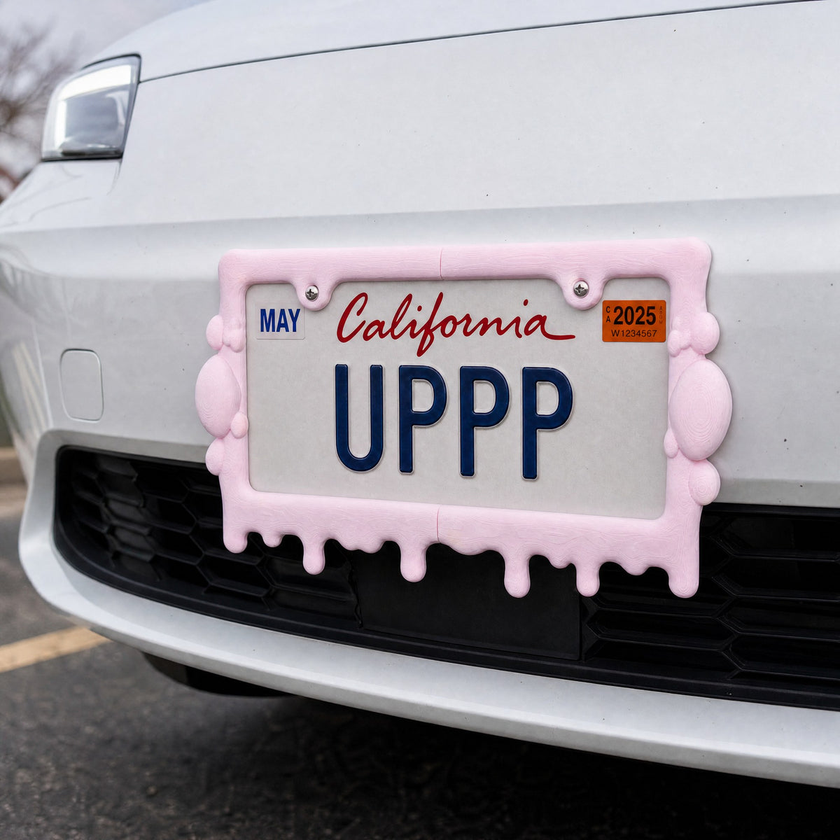 Pink slime license plate frame mounted on the front bumper of a white car