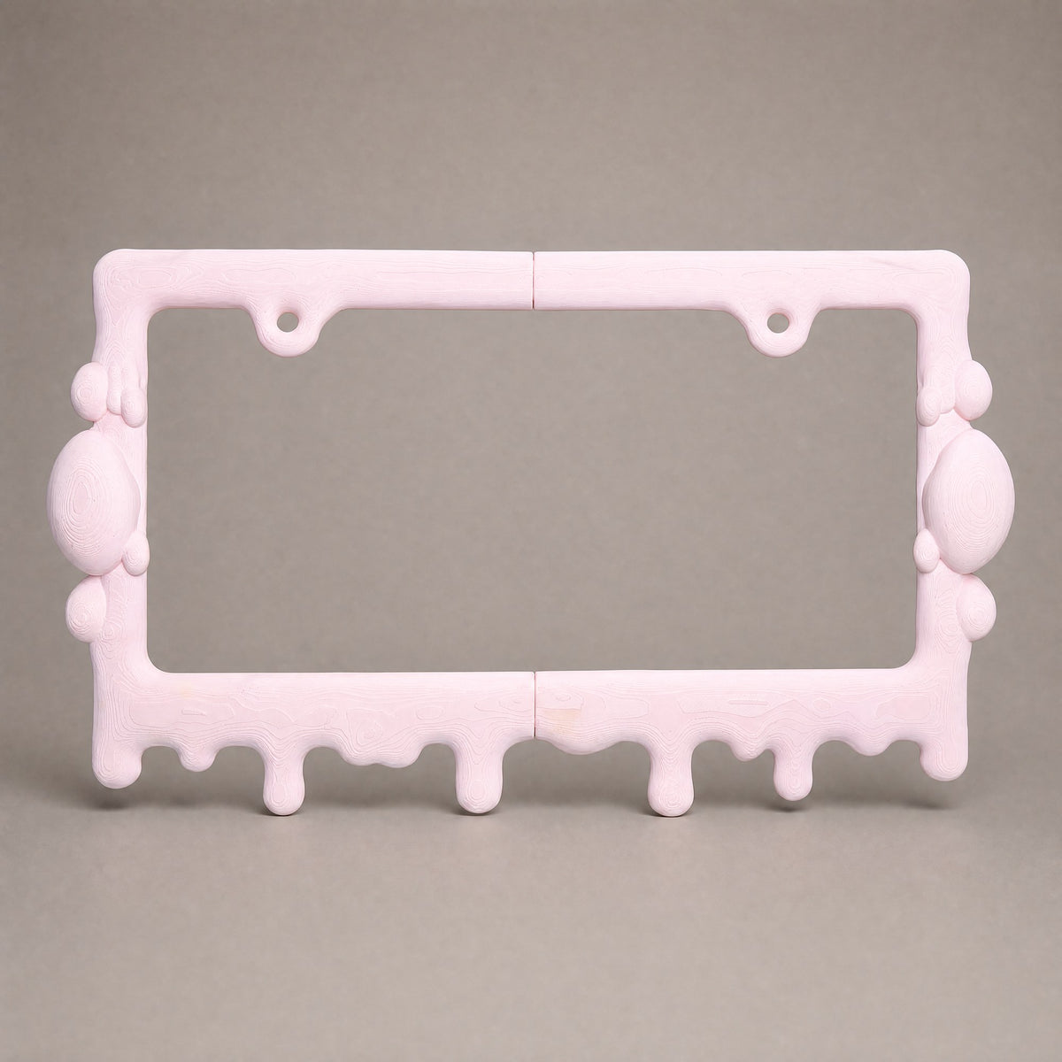 Bubblegum pink drip license plate frame on a neutral grey backdrop