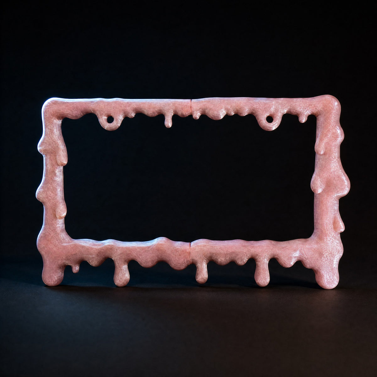 Crystal pink slime license plate frame lit against a black background