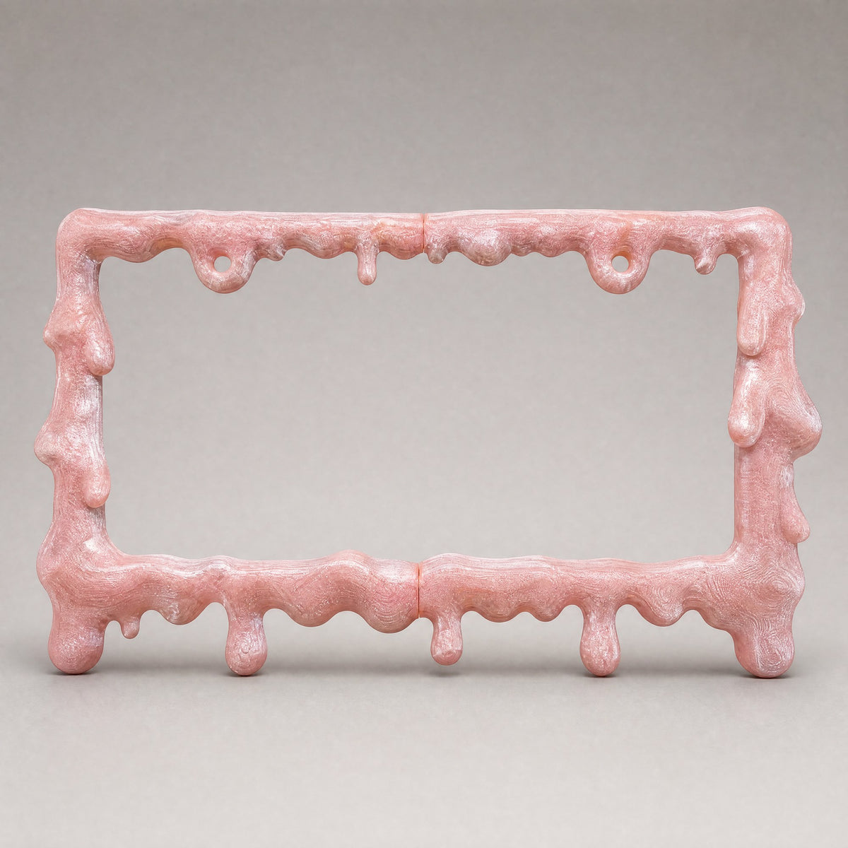 Crystal pink drip license plate frame on a soft grey backdrop