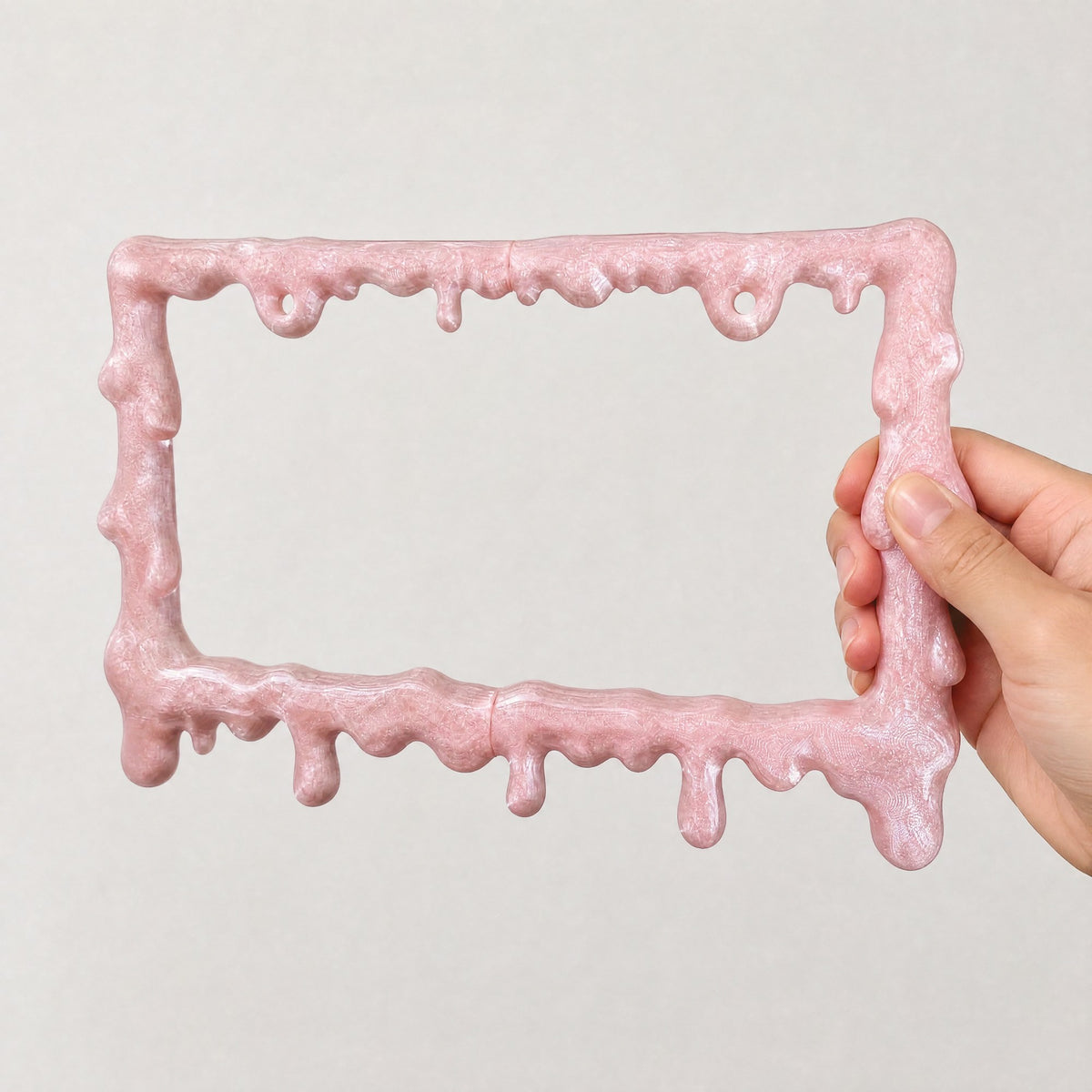 Crystal pink slime license plate frame held in a hand to show its size