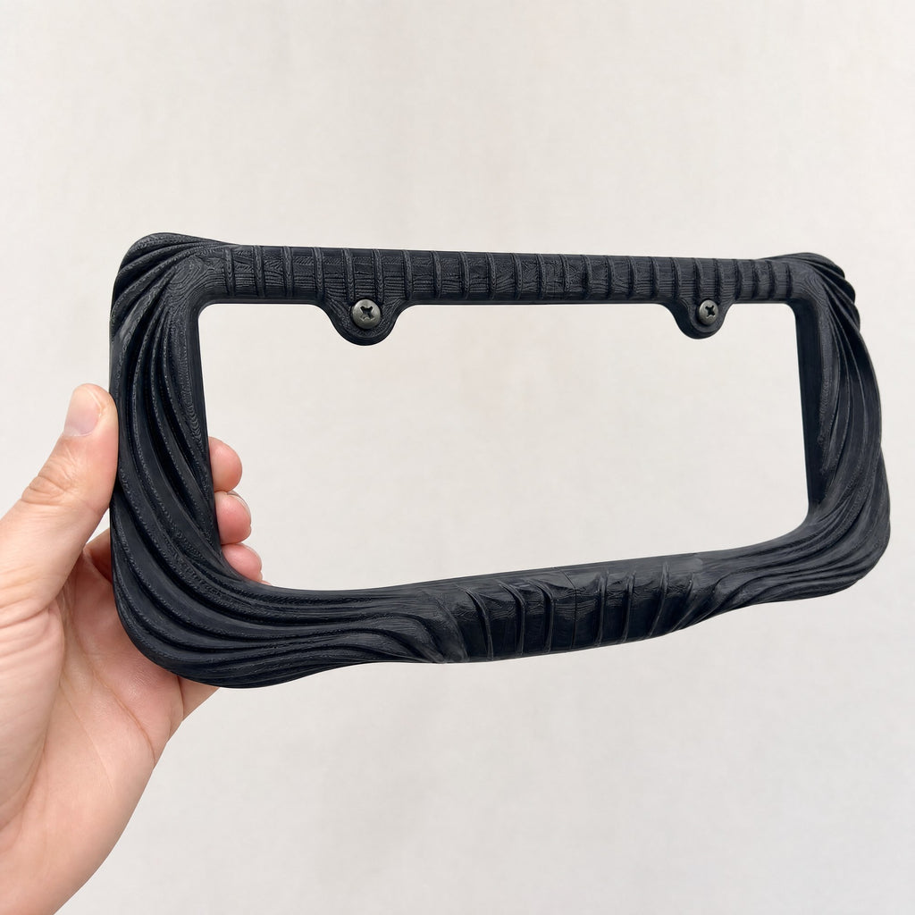 Black Utopia license plate frame held in a hand to show its size