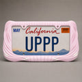 Blush pink draped license plate frame holding a California UPPP plate on a grey background