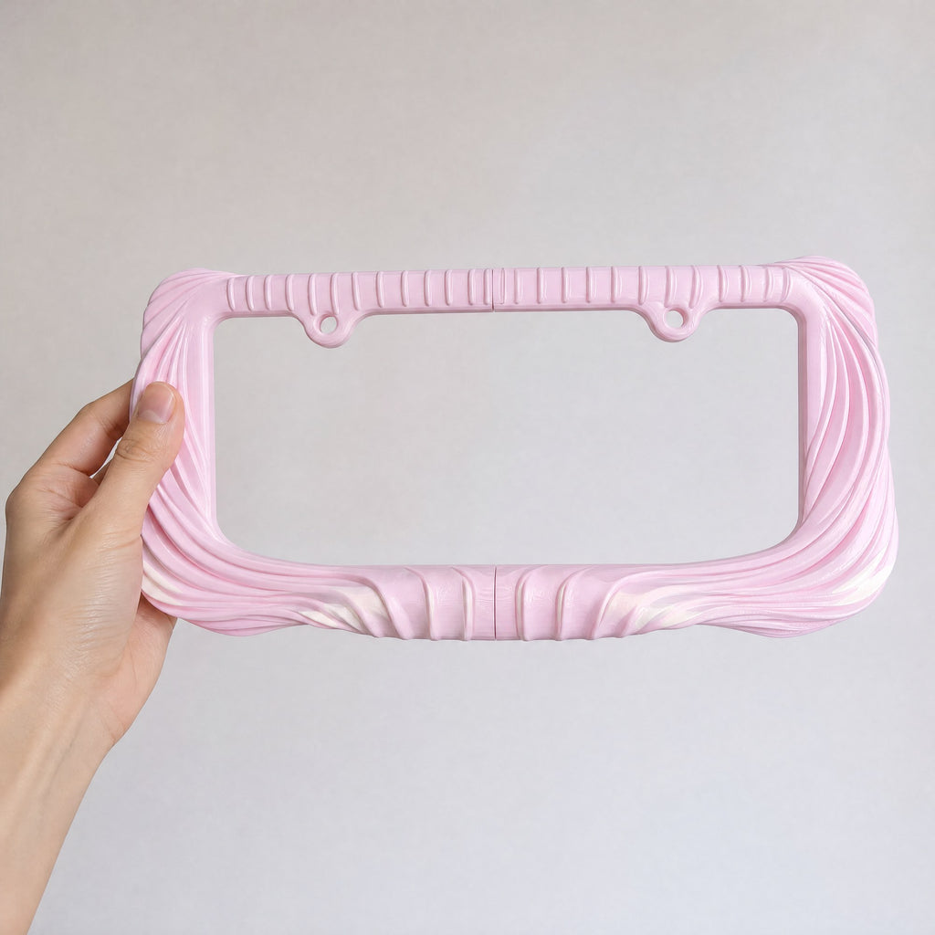 Blush pink Utopia license plate frame held in a hand to show its size