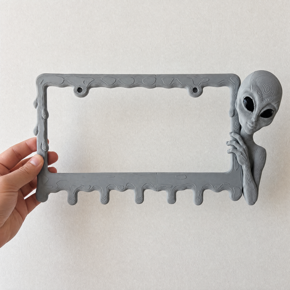Graphite alien frame held in a hand to show its size